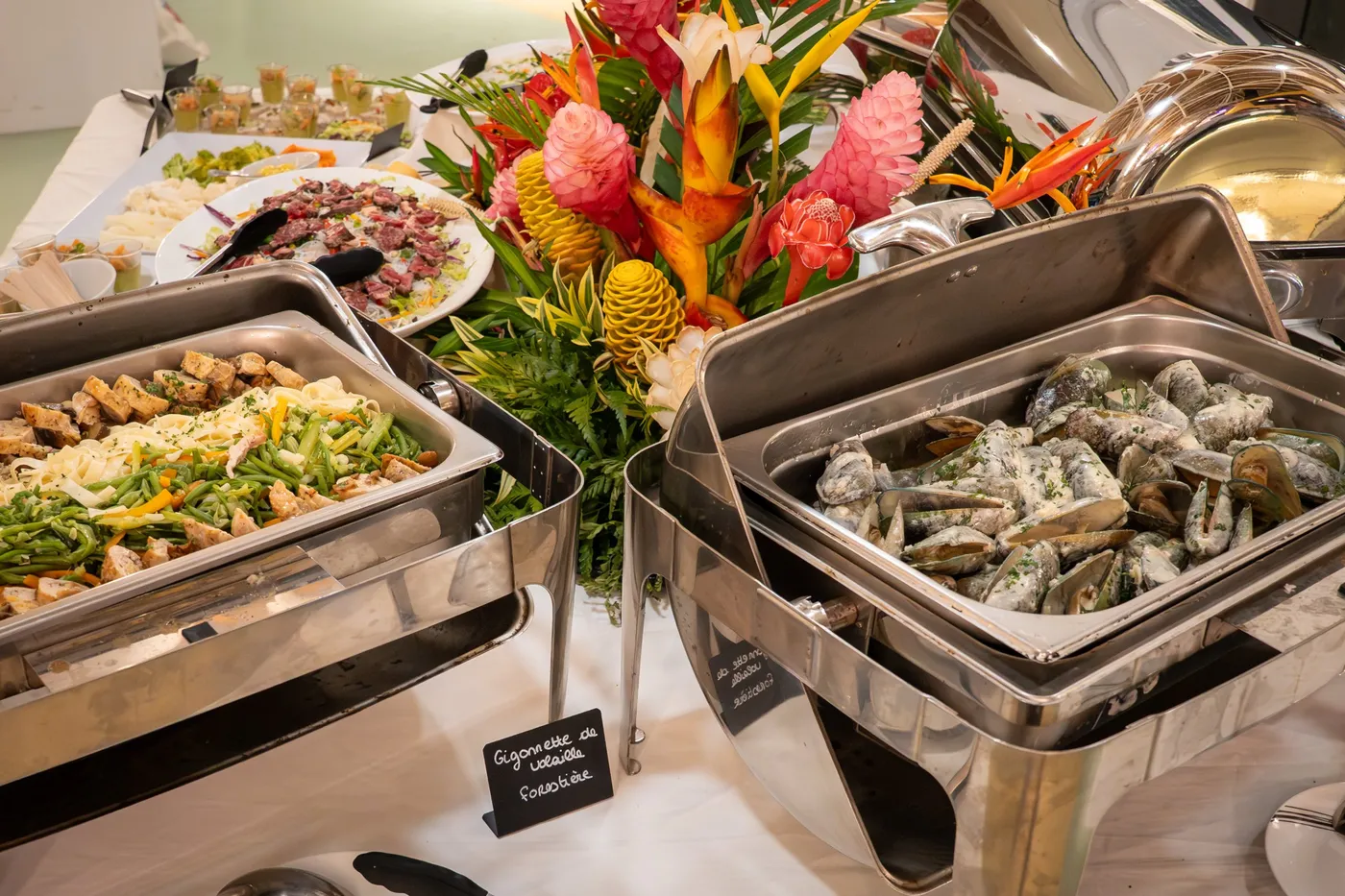 Buffet avec chauffe-plats et composition de fleurs tropicales