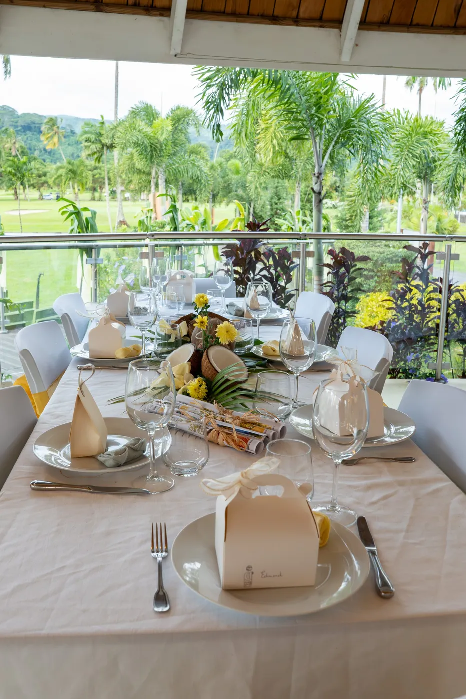 Table dressée avec centre de table en noix de coco et fleurs jaunes, vue sur le golf