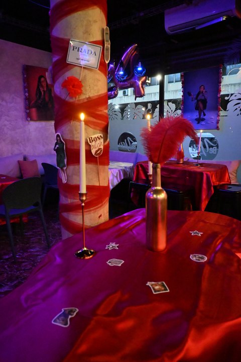 Salle d’événement aux tables rouges, bougies et plume décorative